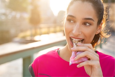 Sporty woman eating energy bar.