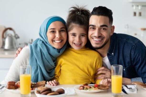 Muslim family enjoying snacks and posing for a picture.