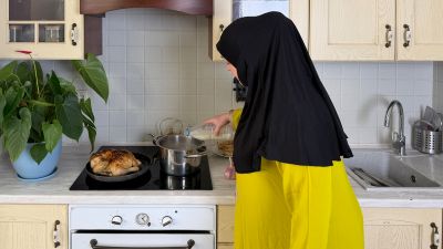 Muslim woman cooking rice and chicken.