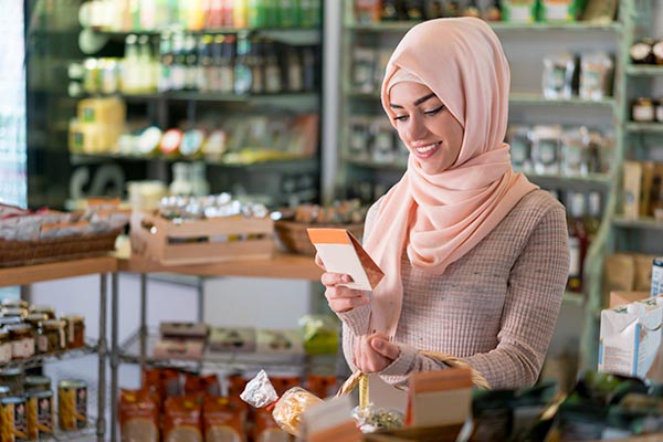 A Muslim woman looking at a package to check if the ingredients are Halal.