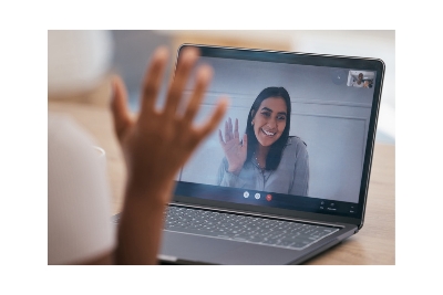 Woman giving hello from social media video call on a laptop.