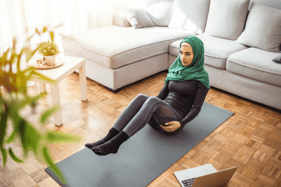 A Muslim woman with hijab doing exercises, likely to be an online fitness trainer.