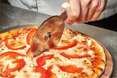 Chef cutting Halal pizza with a pizza cutter.