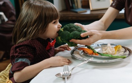 Kid eating Halal broccoli.