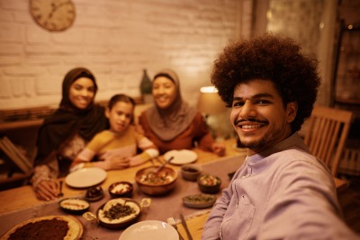Happy Muslim family taking selfie while having Iftar during Ramadan.