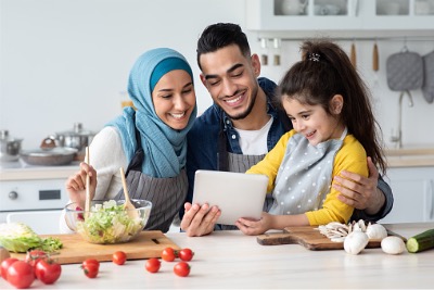 Happy Muslim family using technology for Halal cooking options.