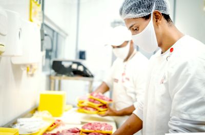 Butcher working in a grocery store, cutting meat.