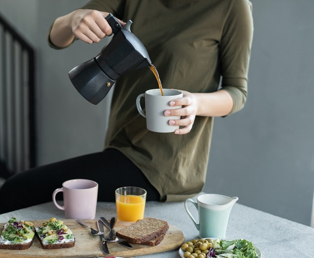 College student pouring a cup of coffee.