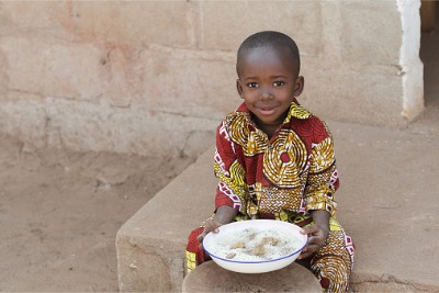 Little black boy from Africa eating rice.