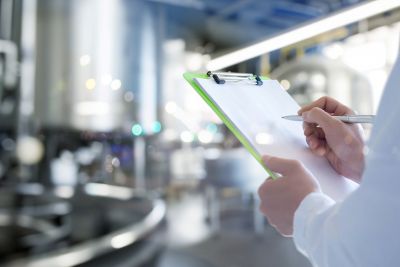 An engineer in a production facility makes entries in a journal.