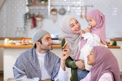 Muslim mother and father feeding their daughter a piece of naan.