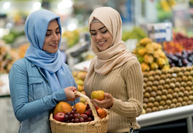 Two Muslim women selecting fruit in a super market.