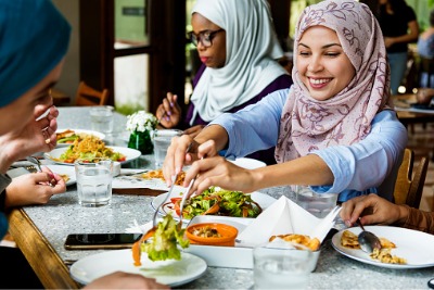 Muslim women friends dining together with happiness.